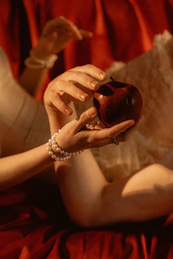 Manos sosteniendo una manzana roja, símbolo del deseo y el autoconocimiento femenino